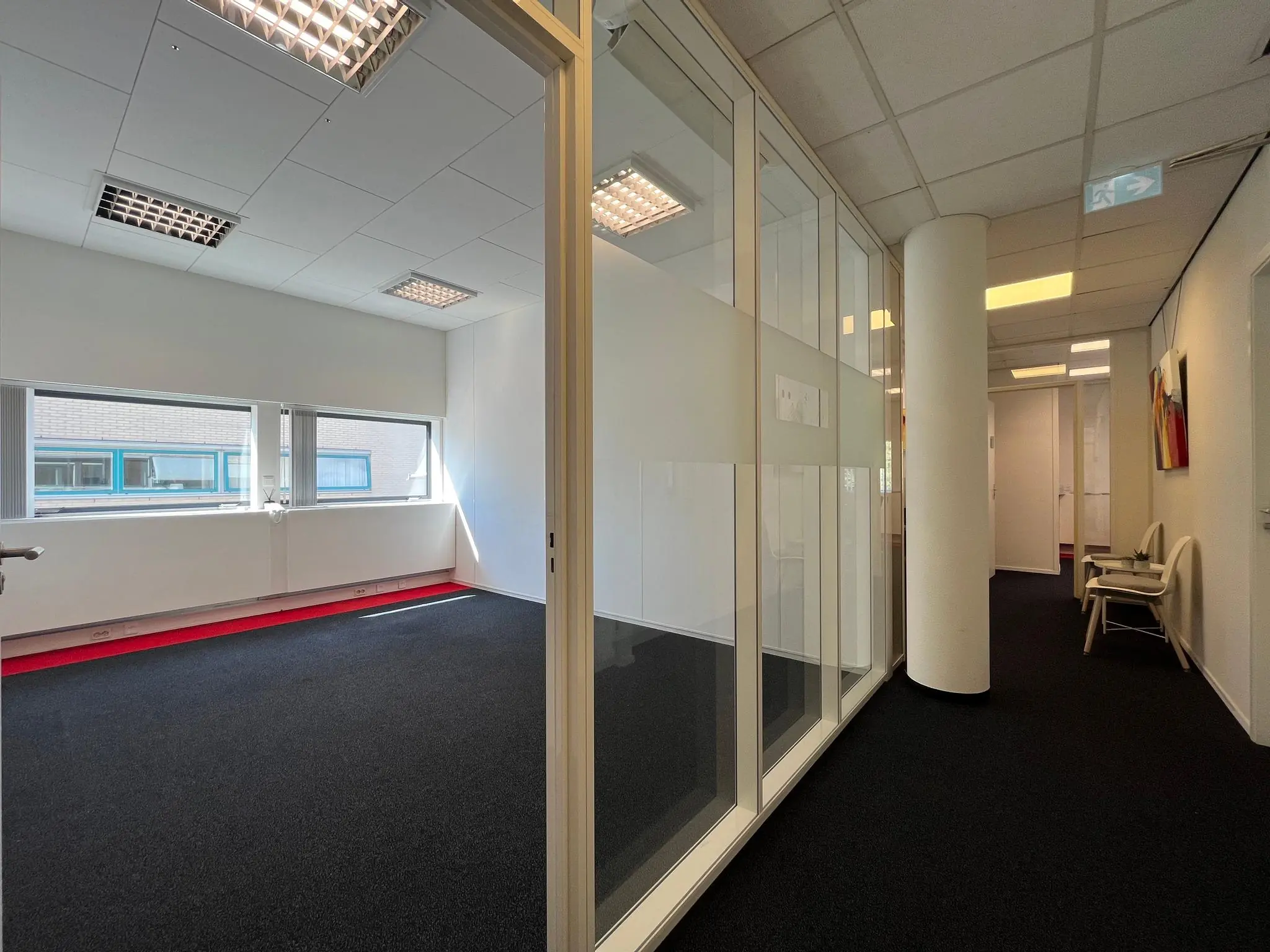 Moderne kantoorgang in Leidse Rijn met glazen wanden en een lege kantoorruimte met grote ramen.